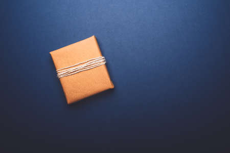 Gift wrapped in recycled brown paper, on blue background with minimalist style wrapping, top view flat layの写真素材