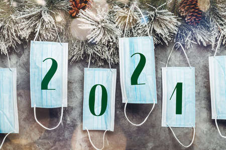 Coronavirus and xmas 2020 concept, 2021 text in masks. Christmas Tree Branches and protective face masks as decoration on grey background, new reality conceptの写真素材