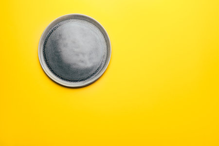 Gray empty ceramic plate on yellow background, trendy colors 2021, Top View, Copy Space