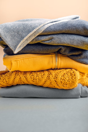 Stacks of folded gray and yellow womens clothing on yellow background