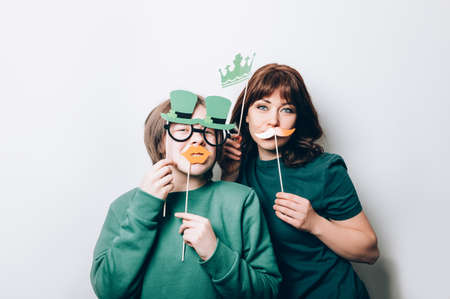Young girl and woman are preparing for the St Patricks Day party with photo booth props, Ireland traditional holiday, 17 Marchの写真素材