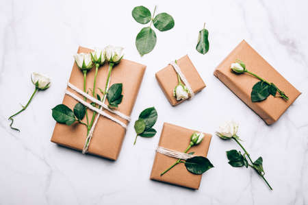 Gift wrapped in recycled brown paper decorated with real fresh roses, on light background with minimalist style wrapping, top view flat lay, eco friendly and zero waste packagingの写真素材
