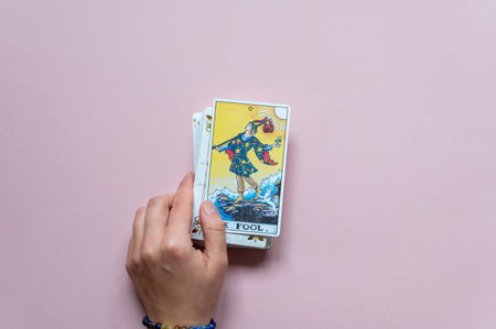 London, UK: 14 October, 2022: The 0 or 22 Major Arcana - The Fool Tarot Card of Rider Waite deck in hand on pink backgroundのeditorial素材