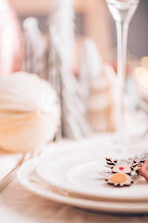Xmas table settings in white and pink colors with christmas trees on background, empty plates and glasses ready for festive dinner and partyの写真素材