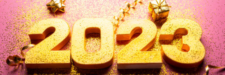 Happy New Year 2023. Golden digits 2023 with glitter and xmas decorations nearby. Holiday Party...