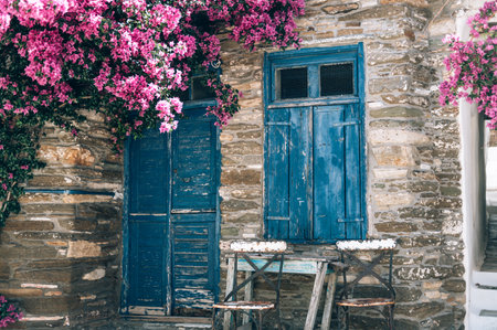 Empty cafe tables on streets of village of Tinos island with Cycladic houses on background, Cyclades, Greeceの写真素材