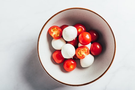 Preparation for Classic italian salad caprese served in original form with cherry tomatoes and mini mozarella pearlsの写真素材