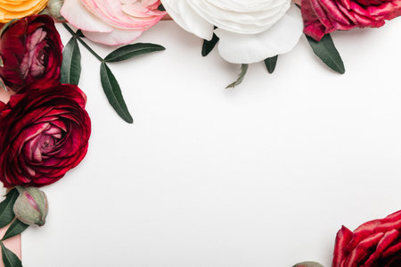 Tender ranunculus flowers as flatlay on pink background with copy space and blank card. Bunch of Persian buttercup in floral arrangements, top viewの写真素材