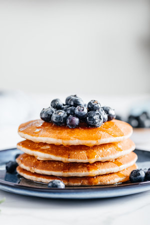 Fresh American Pancakes with blueberries and maple syrup on blue plate