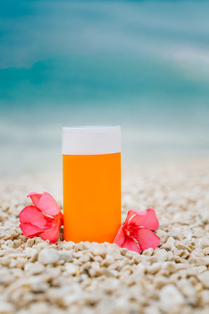 Bright sunscreen bottle on pebble beach with sea as background. Concept of minimalist design of advertisement of sunscreen or cosmetics. Protection against ultraviolet rays or harmful effects of sunの写真素材