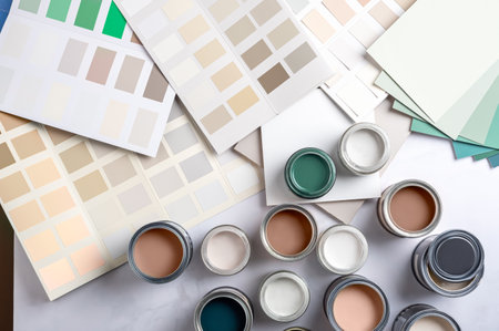 Tiny sample paint cans during house renovation, process of choosing paint for the walls, Mocha Mousse color of the year 2025, color charts on backgroundの写真素材