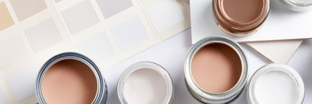 Tiny sample paint cans during house renovation, process of choosing paint for the walls, Mocha Mousse color of the year 2025, color charts on background, banner sizeの写真素材