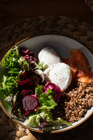 Homemade healthy and balanced breakfast from buckwheat, smoked salmon, salad leaves, beetroot, and poached eggs. Breakfast with strong sun light and shadowsの写真素材