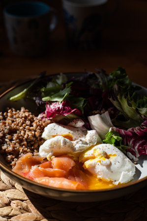 Homemade healthy and balanced breakfast from buckwheat, smoked salmon, salad leaves, beetroot, and poached eggs. Breakfast with strong sun light and shadowsの写真素材