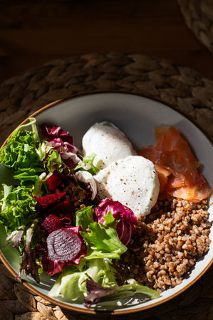 Homemade healthy and balanced breakfast from buckwheat, smoked salmon, salad leaves, beetroot, and poached eggs. Breakfast with strong sun light and shadowsの写真素材