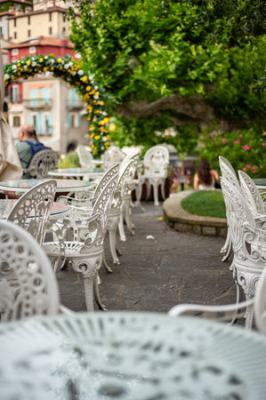 Beautiful cafe with empty chairs on Varenna waterfront on a sunny summer afternoon shoot during windy cloudy day, Lake Como, Lombardy, Italyの写真素材
