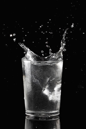 Water splash with ice cube in glasses isolated on blackの写真素材