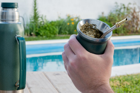 Young man drinking mate in the morning in front of the pool.の写真素材