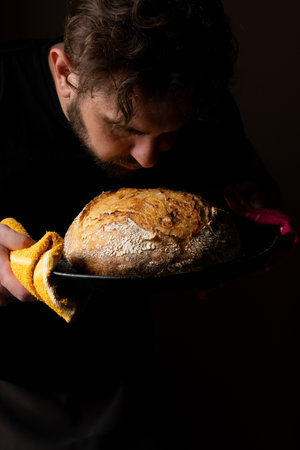 Attractive young Caucasian chef posing with white sourdough bread. The sourdough bread is the...