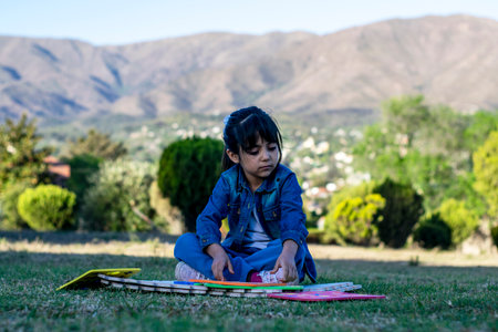Little girl with a beautiful lifestyle learning in the light of day with a beautiful park in the background.の写真素材