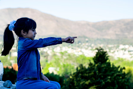 Little girl pointing at a viewpoint with beautiful landscape in the background.