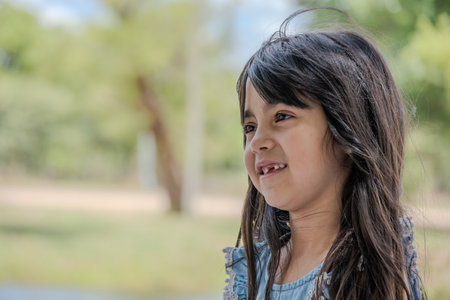 Beautiful little girl pictured in a park while talking.の写真素材