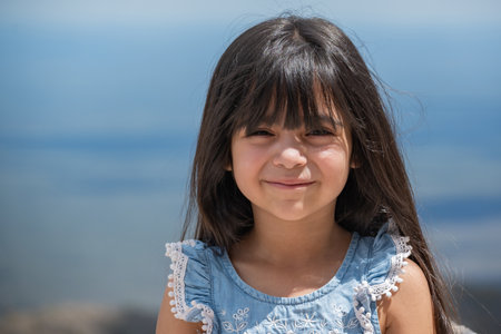 Portrait of a little Hispanic girl on a beautiful blue sky background.の写真素材