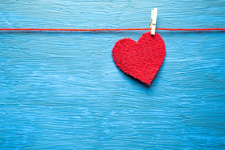 Heart hanging with a clothespin, on a light blue background.