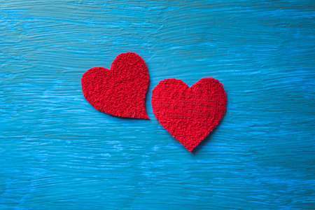 Plush red hearts on a textured light blue table.