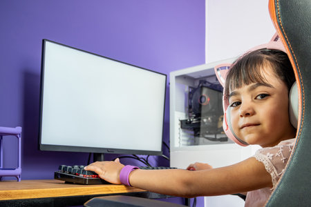 Gamer girl with headphones in front of the computer. She is a childish gamer enjoying time on the...