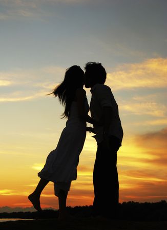 Loving couple in silhouette during sunset.の写真素材