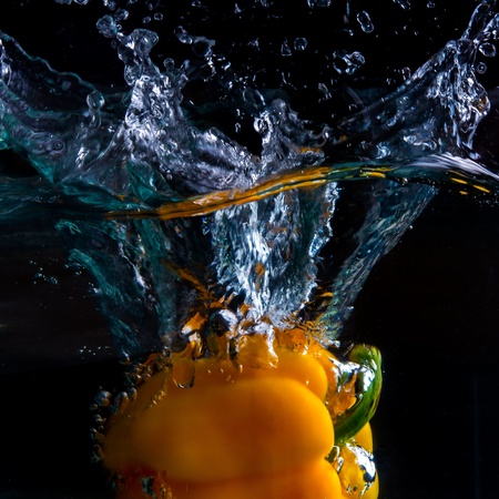 Yellow pepper capsicum splash in black backgroundの写真素材