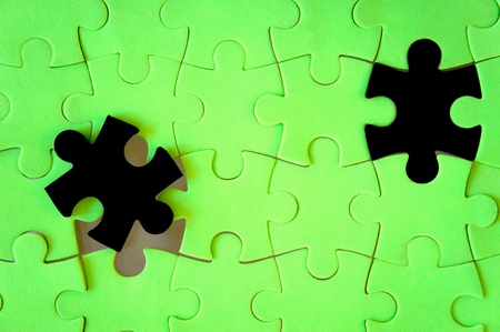 Photo of green puzzle with 2 black pieces lifted.の写真素材