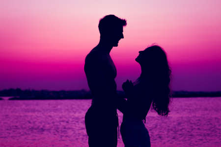 couple in love in the sunset beach - silhouette of young lovers in sunset lightの写真素材