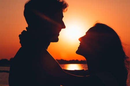 couple in love in the sunset beach - silhouette of young lovers in sunset lightの写真素材