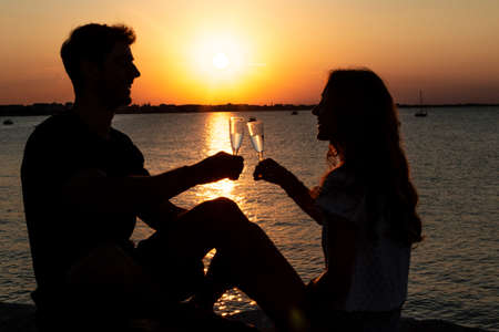couple in love in the sunset beach - two young lovers toast in the sunset lightの写真素材