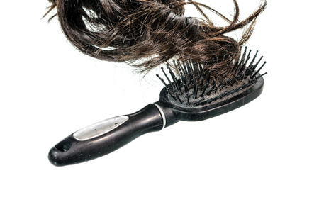 Old black comb with hairs isolated on white background