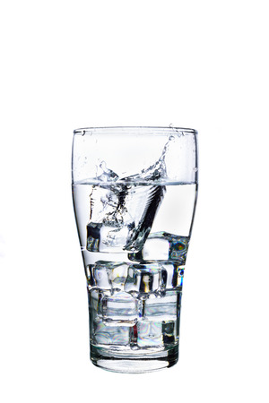 Splashed water with ice cube in glass on white backgroundの写真素材