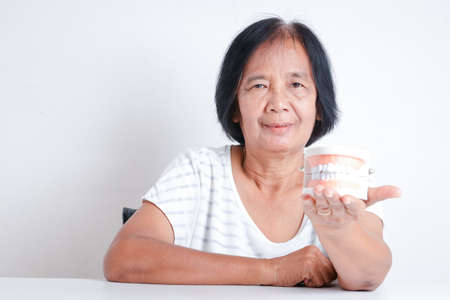 The elderly Asian women hold denture models. Concepts of senior oral health problems and dental careの写真素材