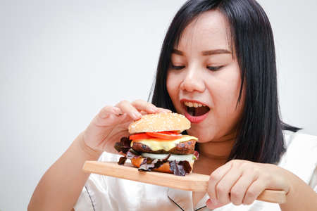 Fat Asian women eat large hamburgers, white background. Health concept. People who are overweight.の写真素材