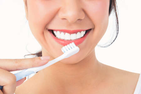 Beautiful smiling woman, clean white teeth, pink lips, hold a toothbrush. Oral care concept. White...