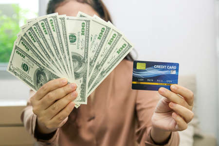 The woman who runs online business holds money and mockup credit cards. Glad to succeed. Startup concept Small entrepreneursの写真素材