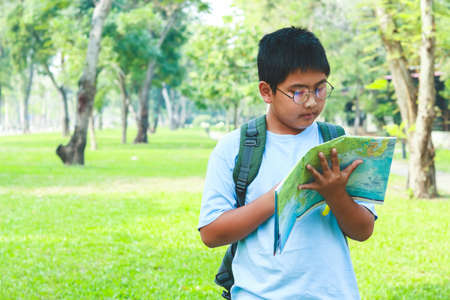 Asian male students Carrying a travel backpack, holding a map to travel to learn