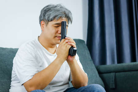 Older men have stress, have business problems and live life. Sitting holding the gun on the sofa...