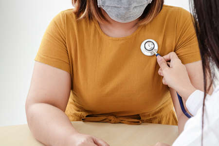 Female doctors use stethoscope to examine the heart of obese female patients. That is at risk for coronavirus infection. The concept of treatment to prevent severe pathogensの写真素材