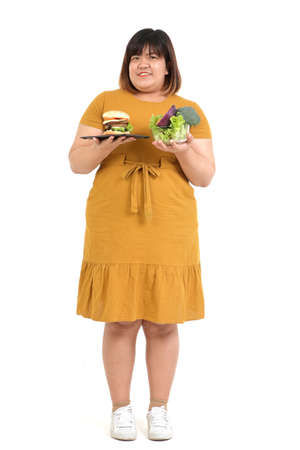 Asian fat woman holds hamburger and salad bowl. On a white background. Weight loss concept Choosing food that is good for the body and health. isolatedの写真素材