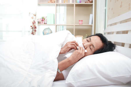 Elderly women In bed in the bedroom She is ill with influenza, high fever, body aches, dry cough, sore throat and runny nose. The concept of health care for older people Medical treatmentの写真素材