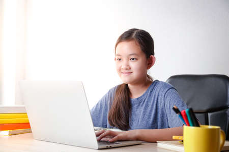 Asian girls study online from home via video call By using a notebook computer to communicate with...