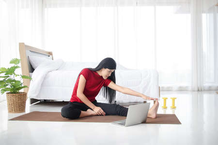 Asian women exercise in the bedroom at home. Along with watching media as well. Health care...