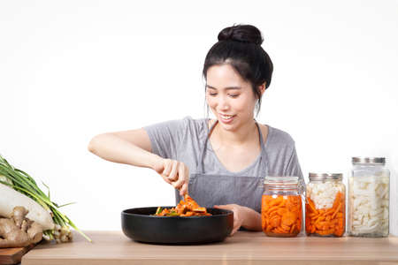 Asian beautiful woman Cooking kimchi Is a Korean fermented food made from vegetables, Chinese cabbage, carrots, radishes, onions, ginger, apples, salt, chillies. White backgroundの写真素材